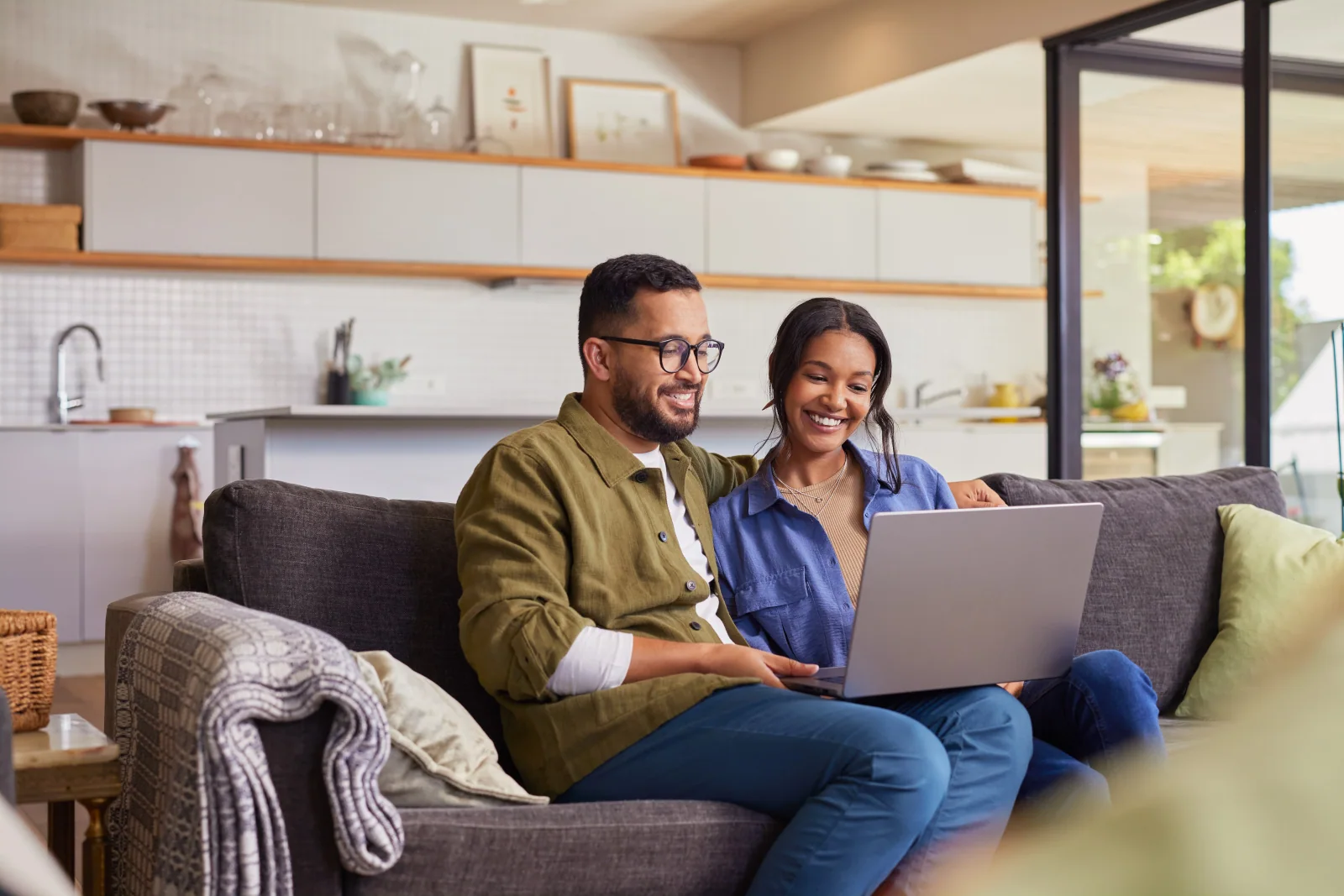 A couple reviewing information on a laptop together on their couch.