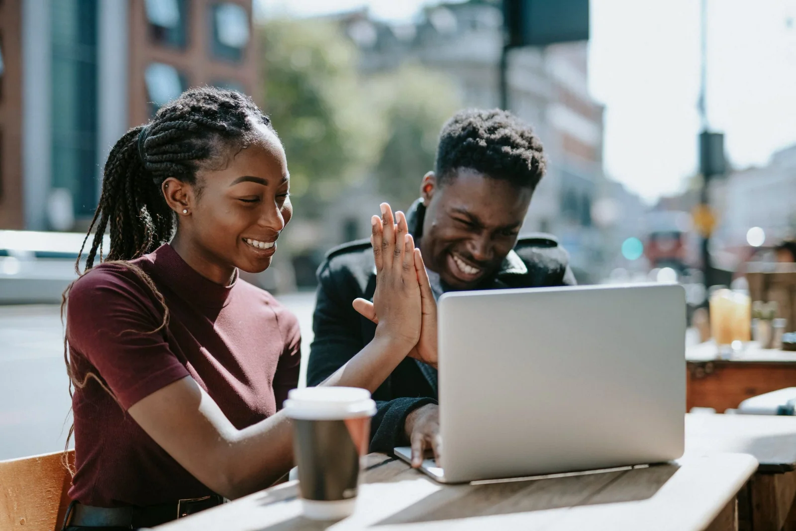 Two people smiling and high-fiving beside a laptop.