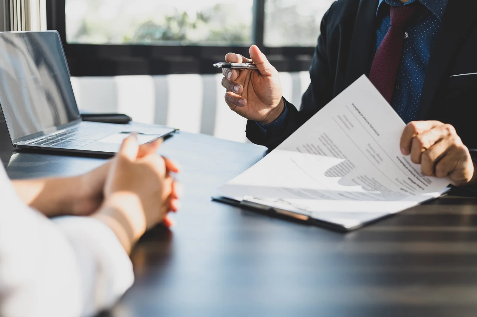 A professional discussing documents across a table with another person.